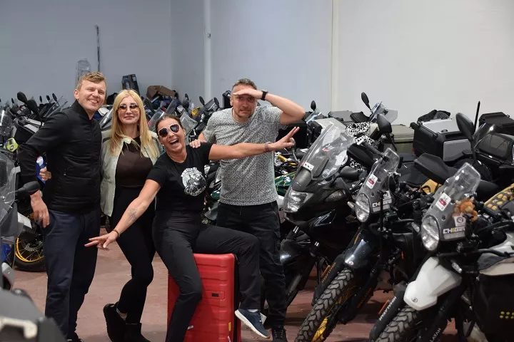 Uśmiechnięty zespół i klienci Motorland.rent w otoczeniu dziesiątek motocykli BMW GS w hali magazynowej w Maladze