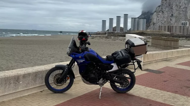 Motocykl Yamaha Tenere 700 z czarnymi kuframi wyprawowymi na tle skały Penon de Ifach w Calpe – wypożyczalnia Motorland.rent