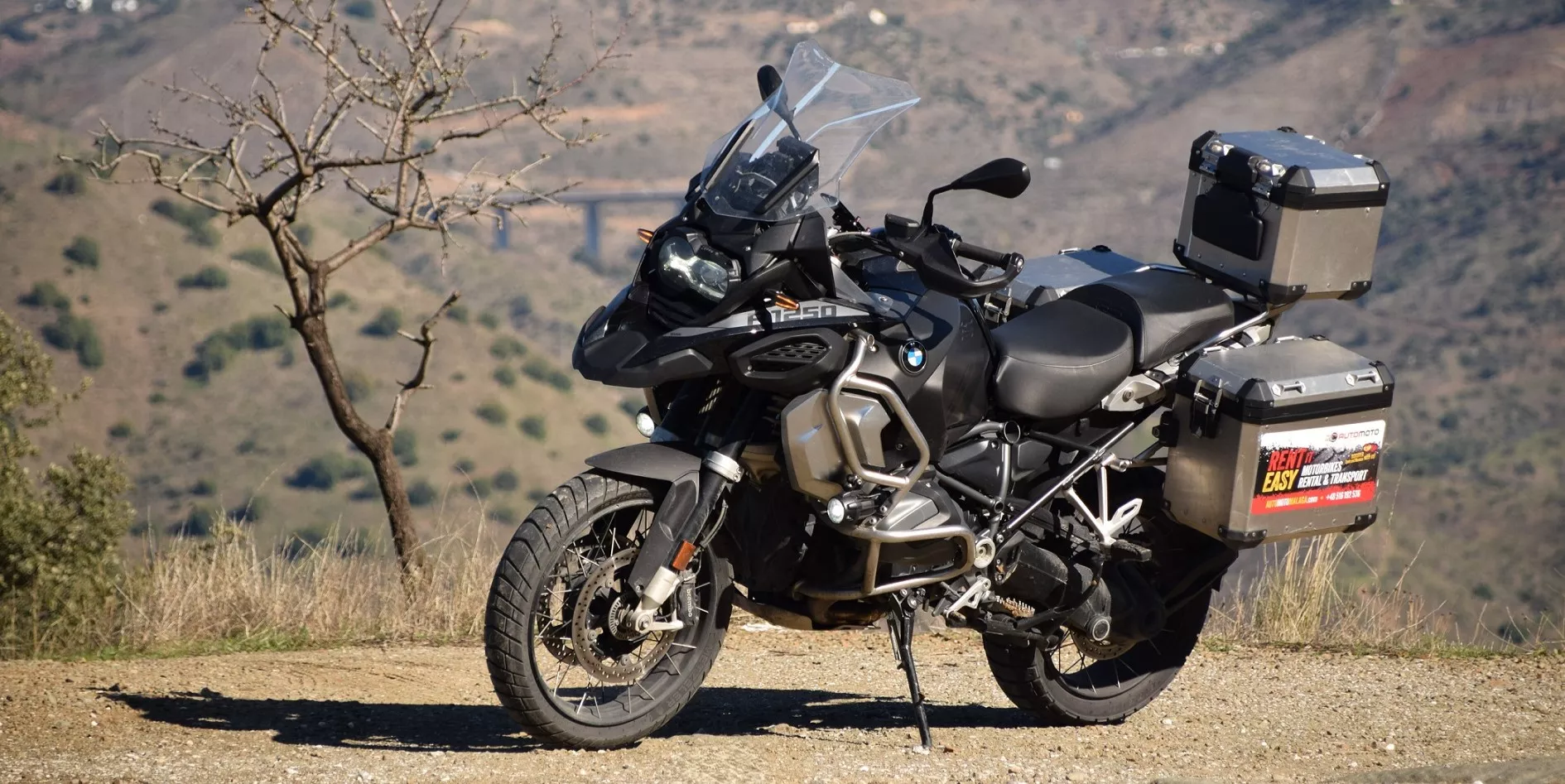 Motocykl BMW R 1250 GS Adventure z kuframi aluminiowymi na punkcie widokowym w hiszpańskich górach – Motorland.rent