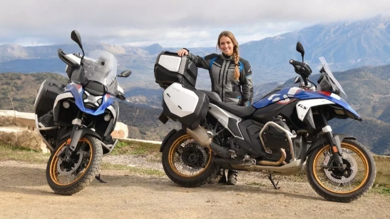 Kobieta w stroju motocyklowym stoi obok dwóch motocykli BMW GS przygotowanych do wyprawy, w tle góry w okolicach Malagi w Hiszpanii.